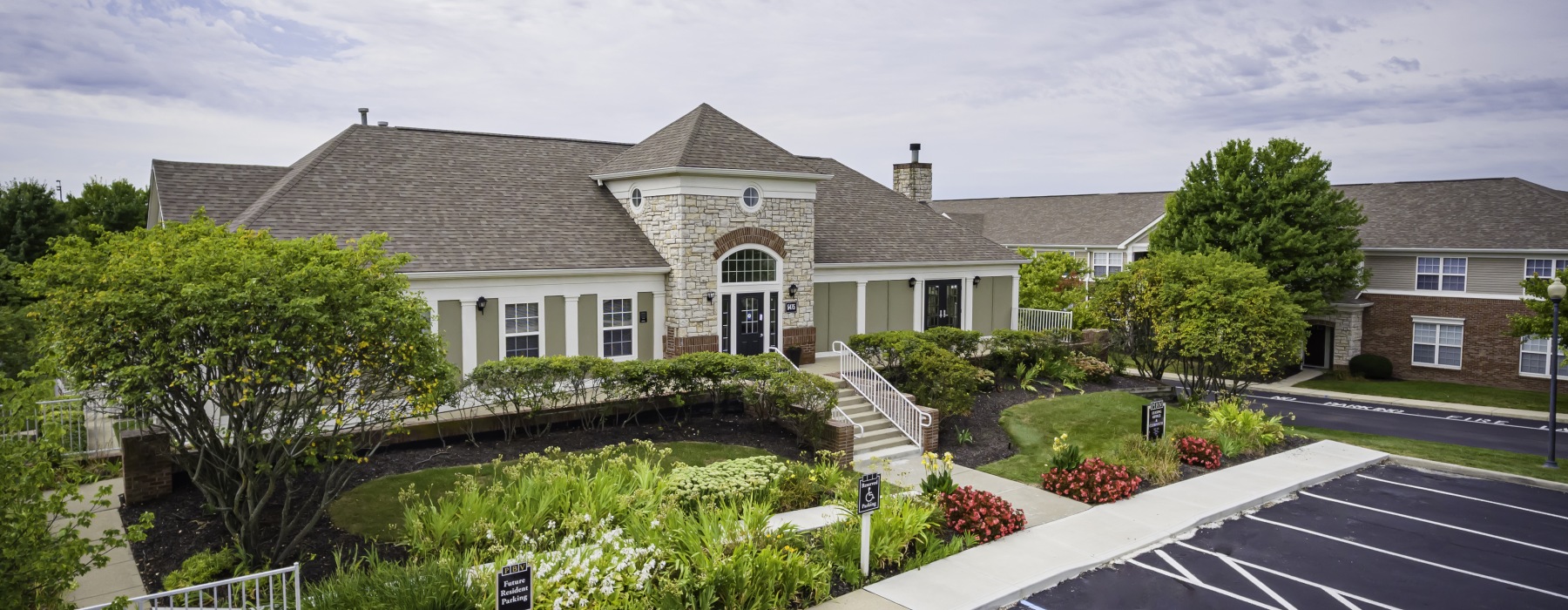 Apartment leasing building exterior with greenery and parking spaces